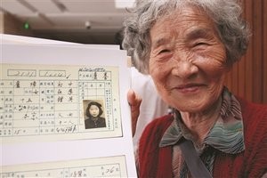 Xu Zhang, 84, shows her teen photo on her family's household registration card [Yangtze Evening Post/Zhang Ke]